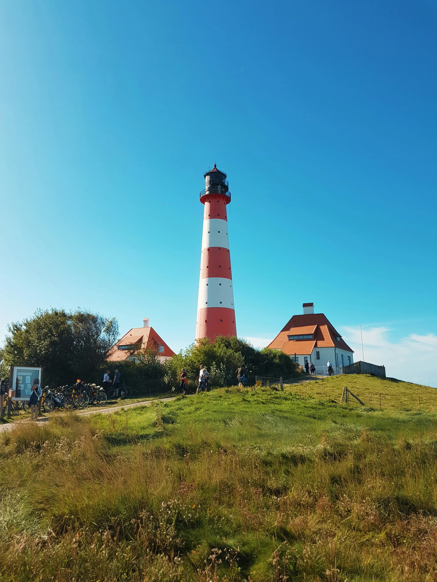 a big red and white lighthouse standing on a grassy hill