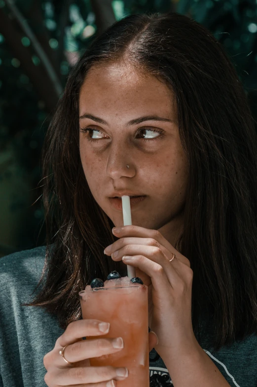 a woman holds a straw and looks at the camera