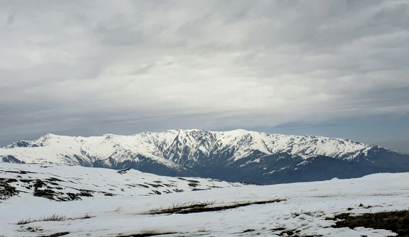 a skier standing in the middle of the snow looking out at the mountains