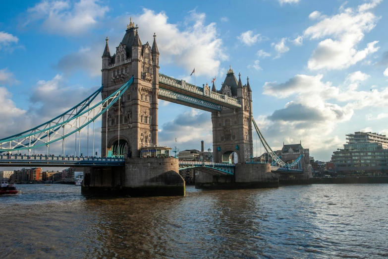 the tower bridge is across the water with boats in it