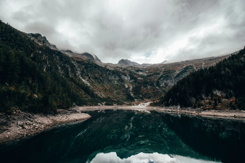 a small body of water sitting in the middle of a lush green mountain