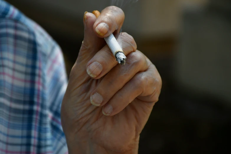 an elderly woman holds a cigarette in her hands