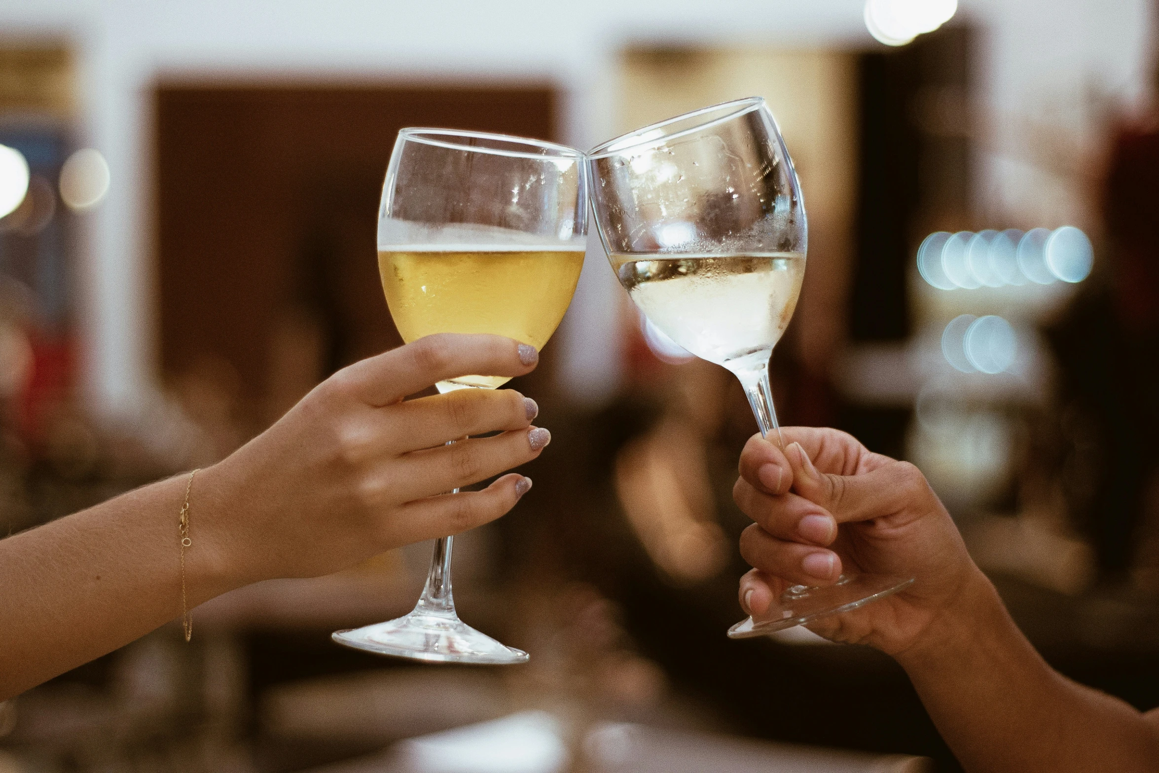 two hands toasting wine glasses at a restaurant