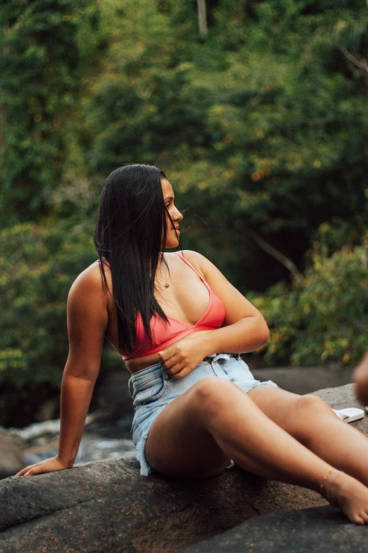 a woman in pink tank top sitting on rock