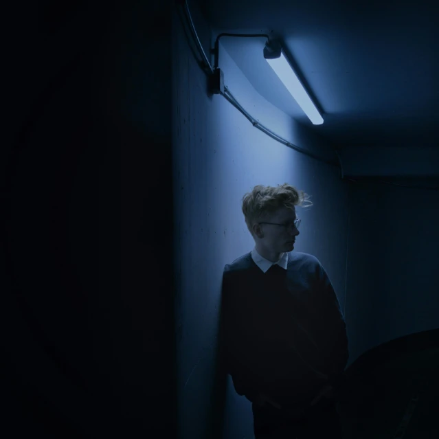 a young person standing alone in a dark room