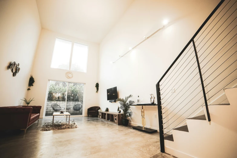 the stairs lead up to a living room that has large windows and lots of seating