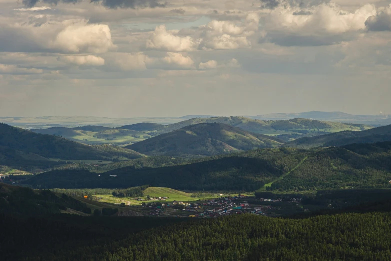 a field sitting between two mountains under a cloudy sky