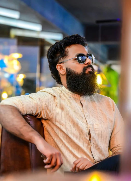 a bearded man with shades on sits at a table