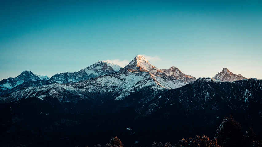 the sun is set over the mountain tops in the blue sky