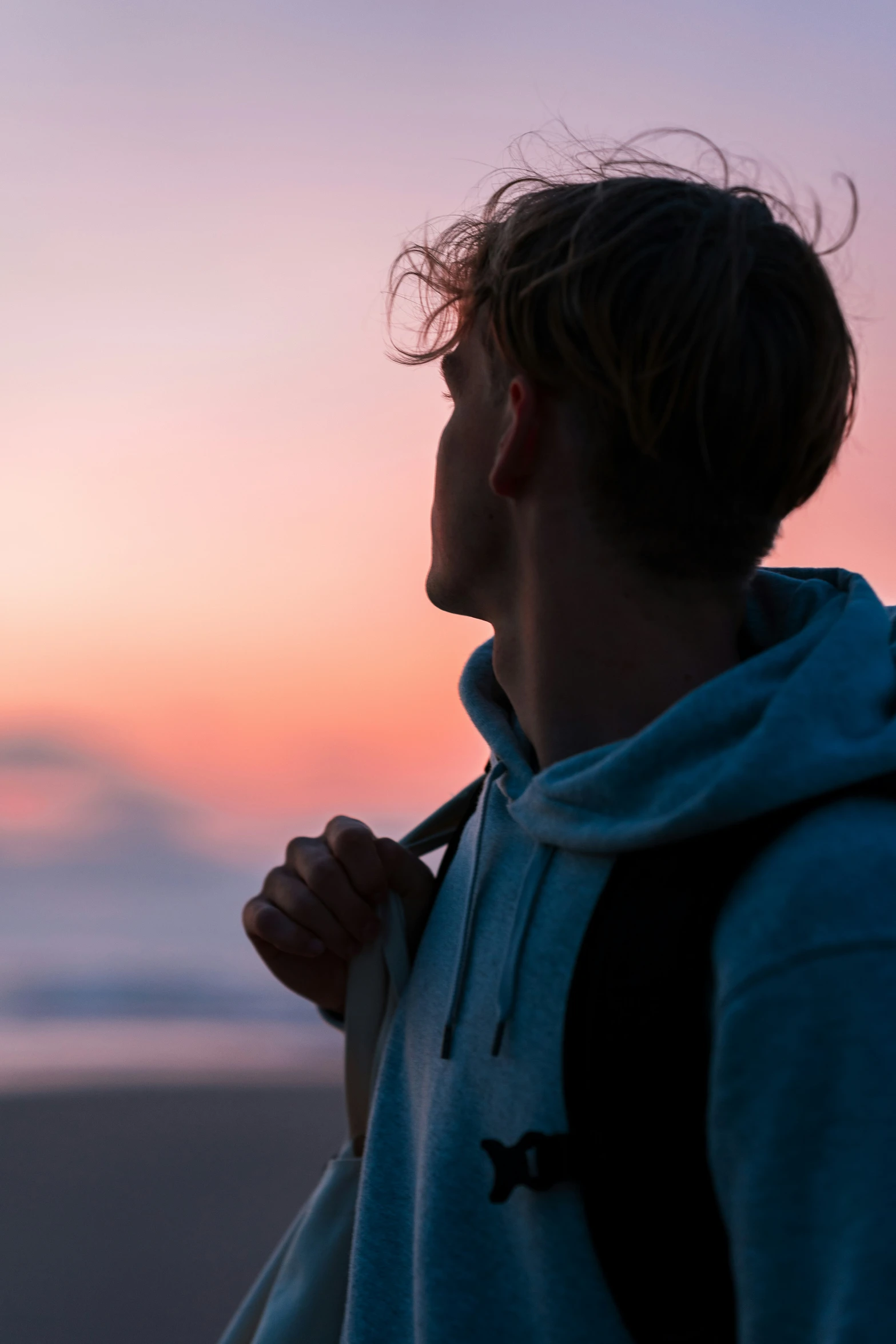 a man in a sweatshirt looking away over the ocean