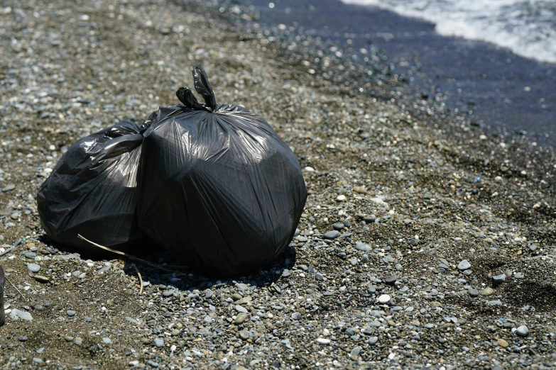 a trash bag sitting on the sand next to the ocean