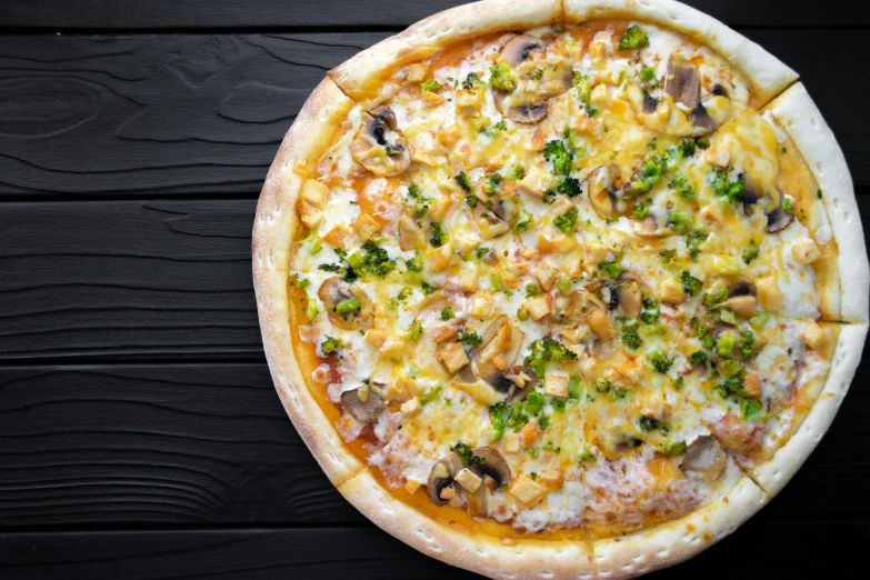 a pizza with mushrooms, broccoli and cheese on it