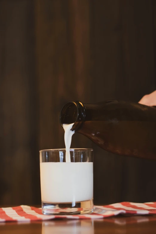 someone pouring soing in a glass with milk