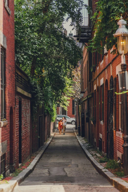 two people walking down an alleyway on the side