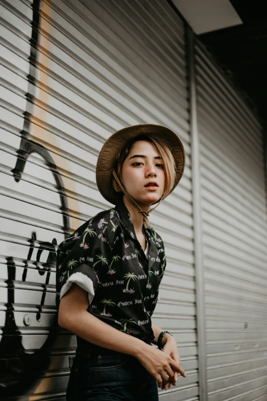 a young lady standing against a wall in front of a graffiti filled building