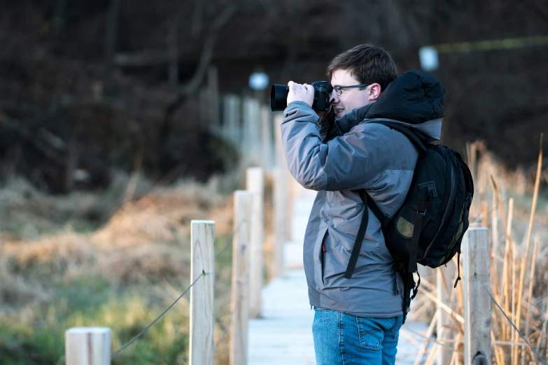 the man in glasses is taking pos with his camera