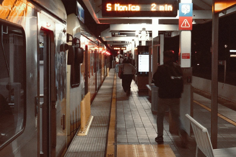 passengers exit a train from a platform in a city at night