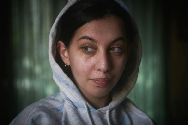 a woman with a hooded over her head in a dark room