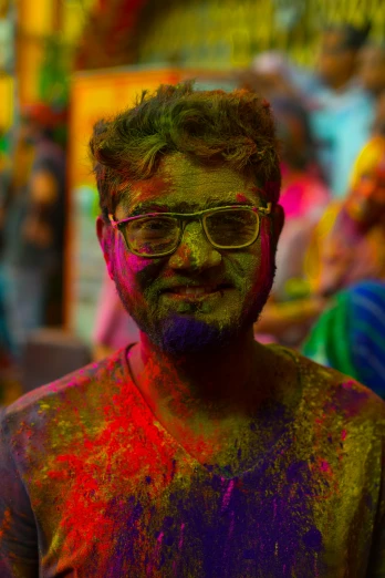 a person covered in colorful powder standing and smiling