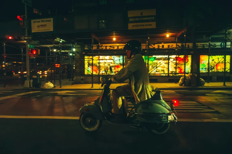 a man on a moped riding through the city at night