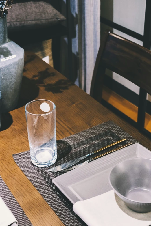 a wooden table with a white plate and silverware