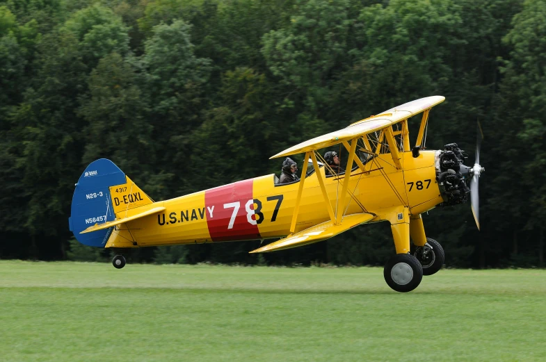 a yellow and red plane flying over a green field