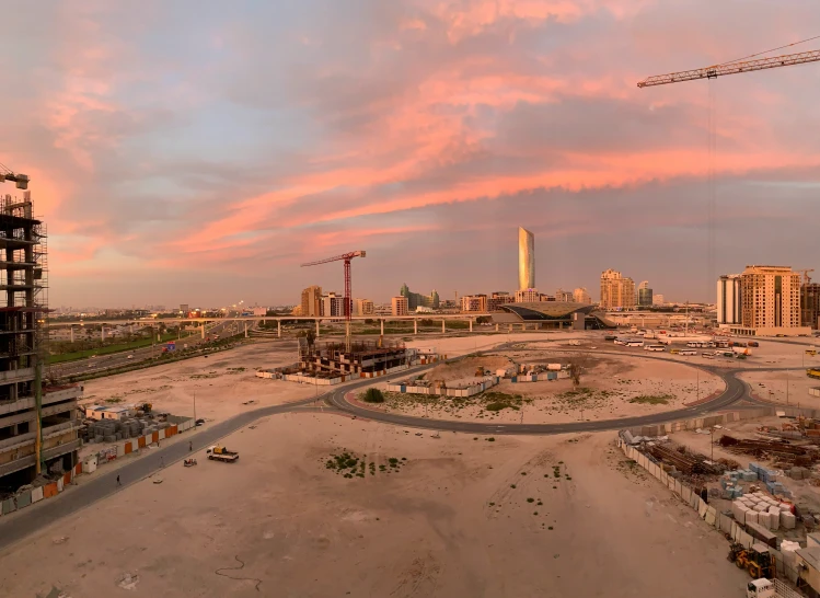 an area with various buildings, cranes and some dirt