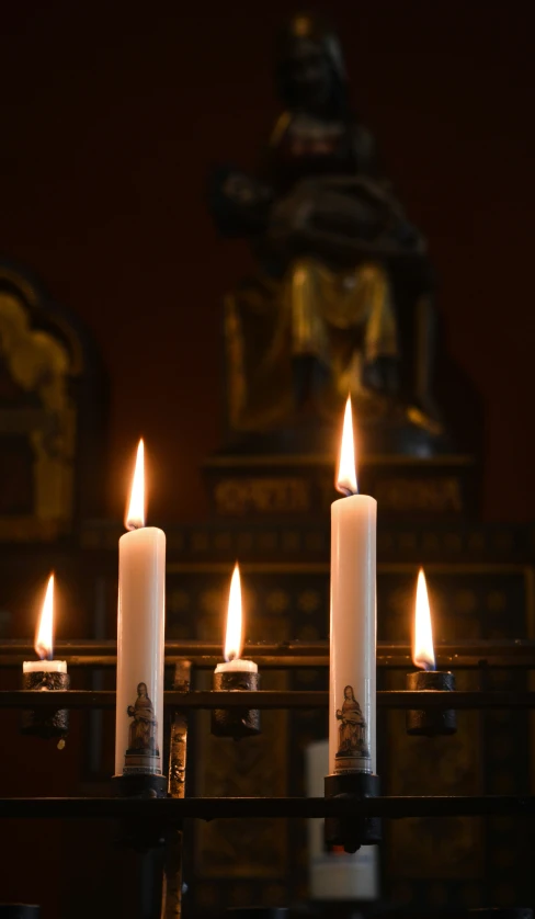 candles sit on a church alter in front of a statue