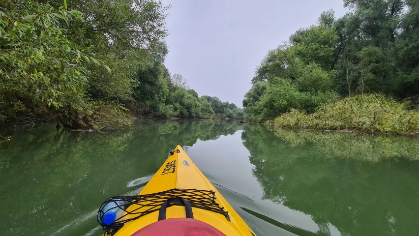 the man in yellow kayaks is paddling down a river