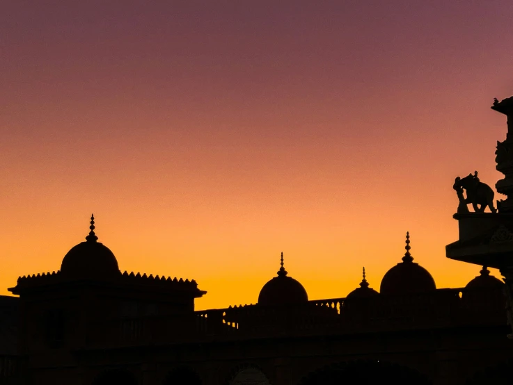 silhouettes of buildings against an orange sunset