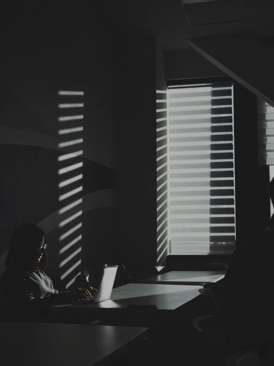 people are sitting at a table with laptops in the dark