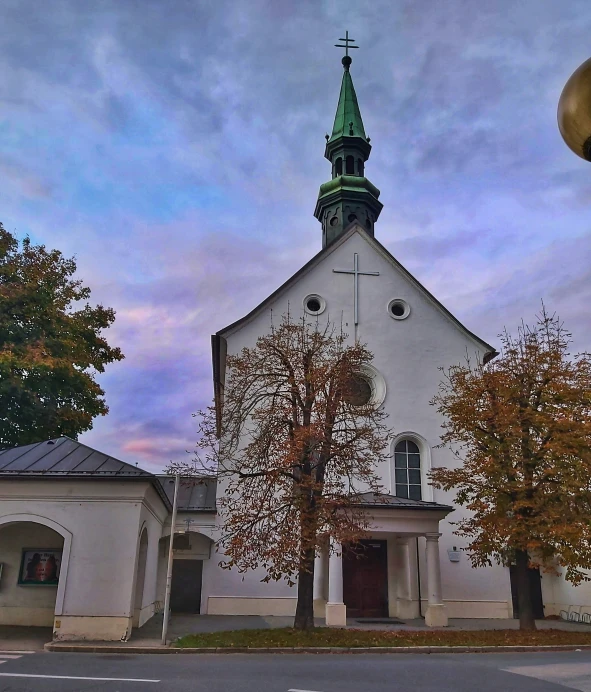 an old white church sitting next to a tree