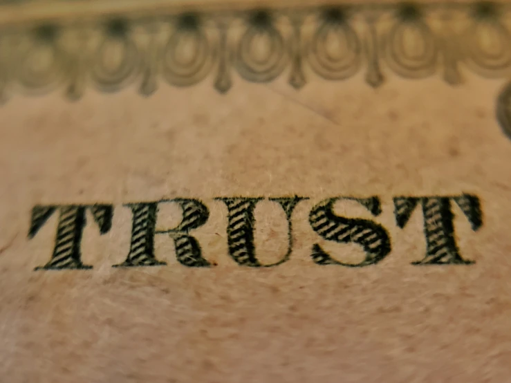 close up view of the word trust on a hundred dollar bill