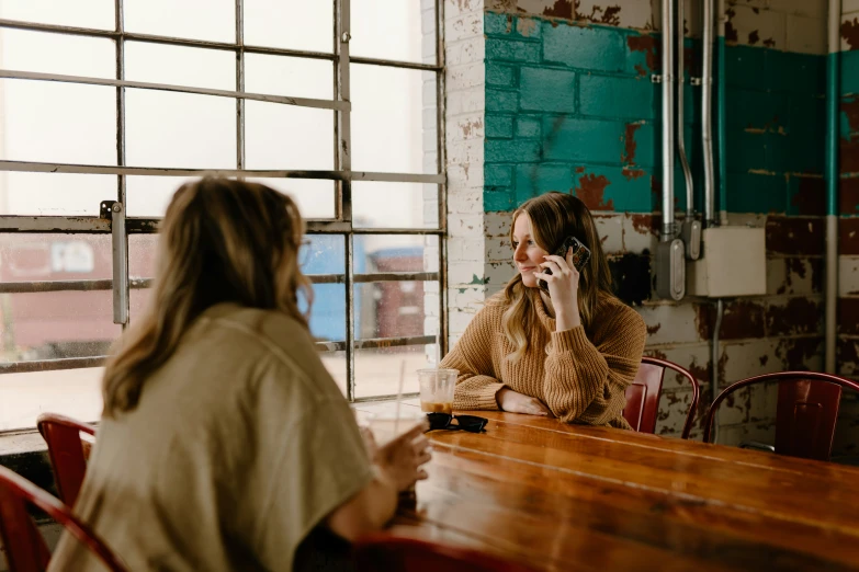 a woman is talking on her cell phone as she talks to another woman