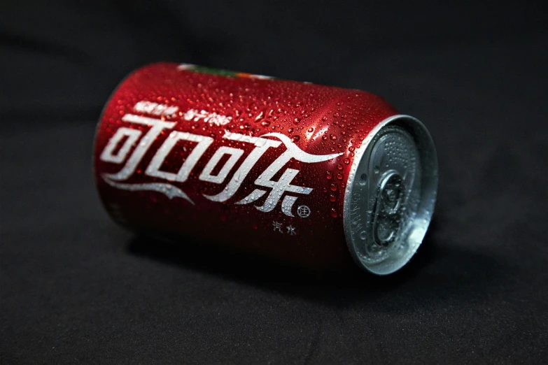 red can of coca - cola sitting on a black background