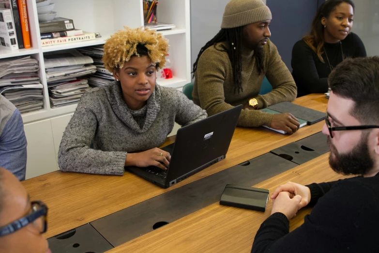 a group of young people sit around a wooden table