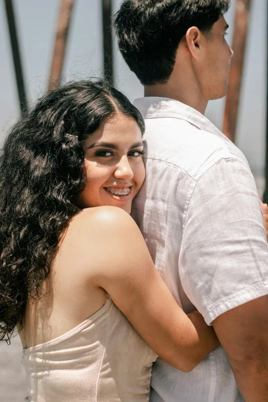 a man and woman are hugging near a bridge