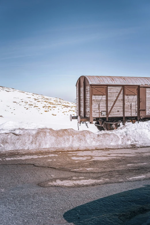 a train car sitting next to a snowy mountain