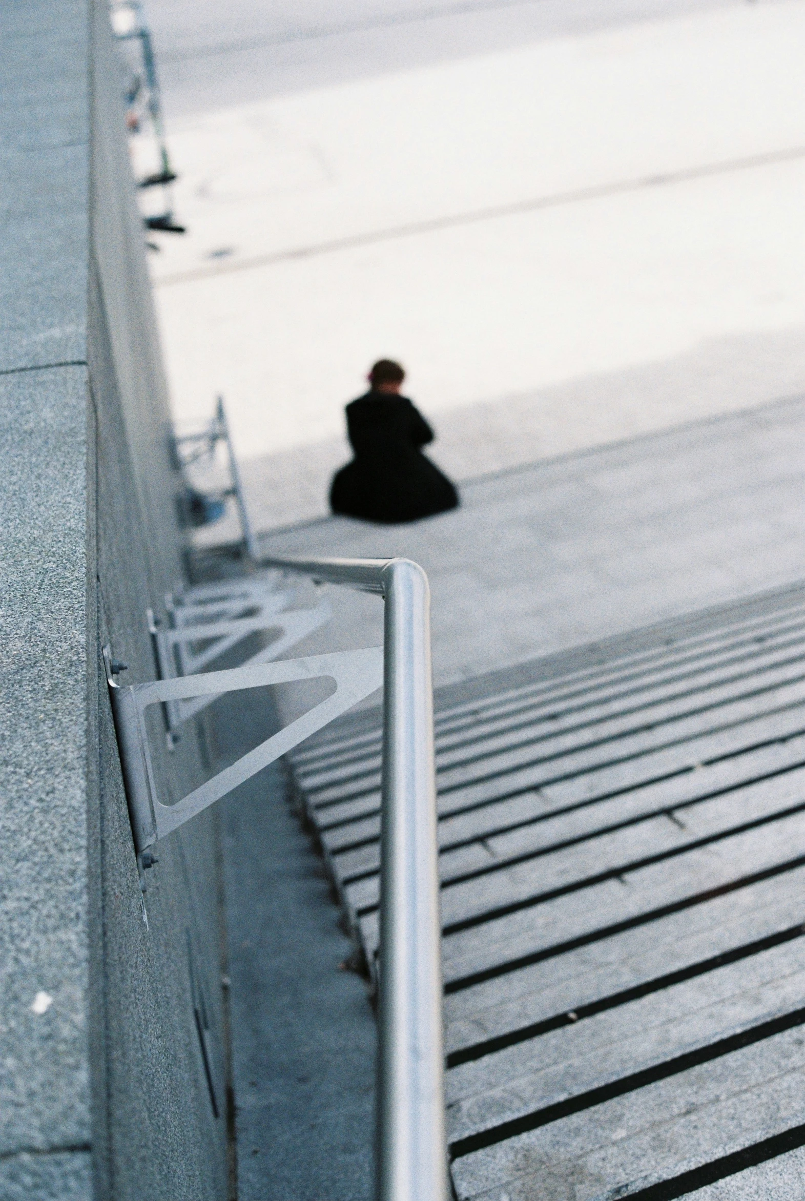 people walk down a sidewalk near the edge of a pedestrian rail