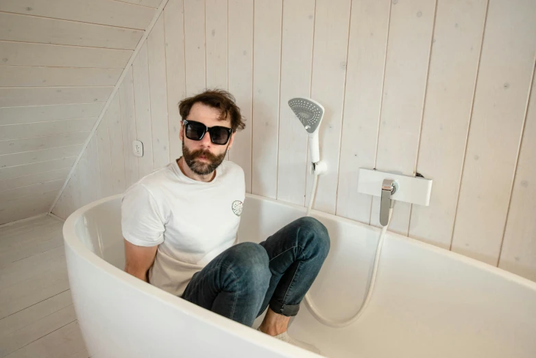 man sitting in bathtub with steam turbine behind him