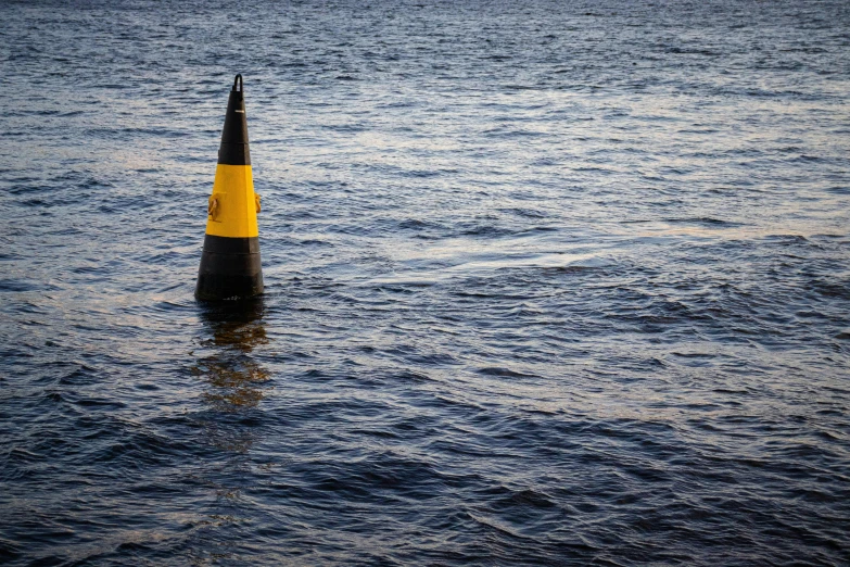 an image of a yellow and black hazard cone in the water