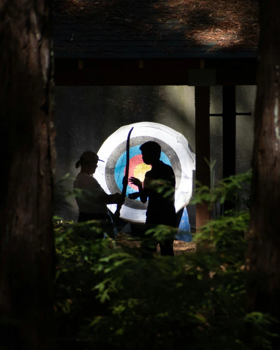 a couple holding an umbrella with trees behind them