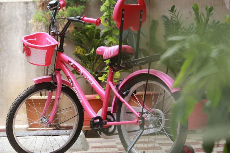 pink children's bicycle with basket in residential courtyard