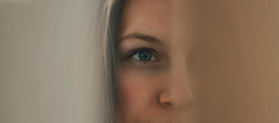 the young woman's blue eyes are appearing through the gray wall