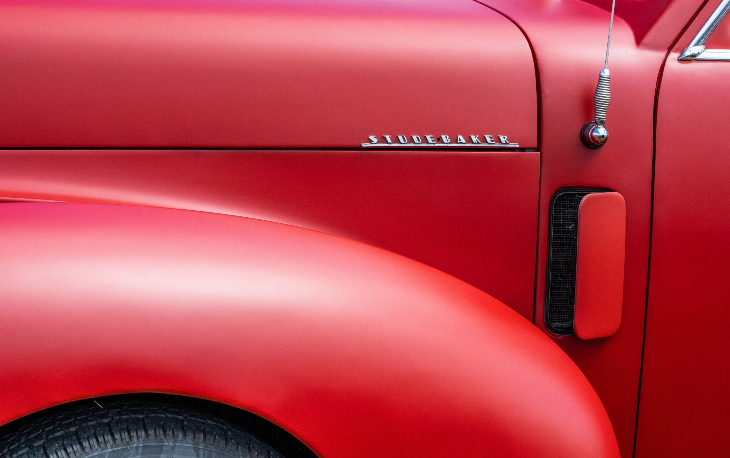 a close up view of the emblem on a red classic car