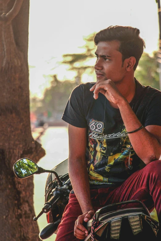 a man in black t - shirt sitting on the back of a motorcycle