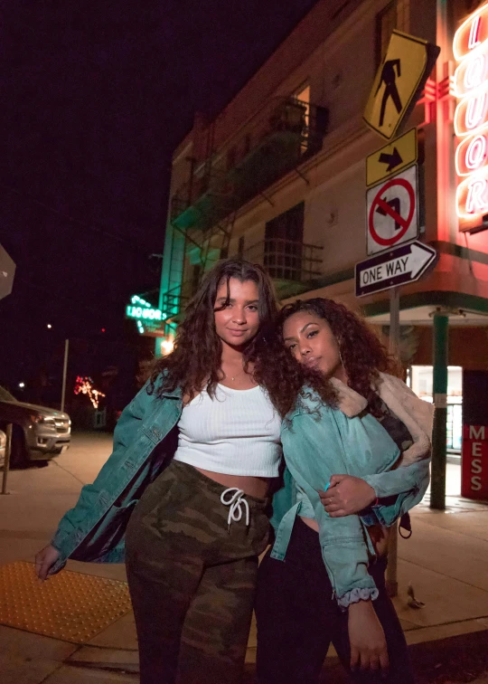 two young women stand next to a no parking sign