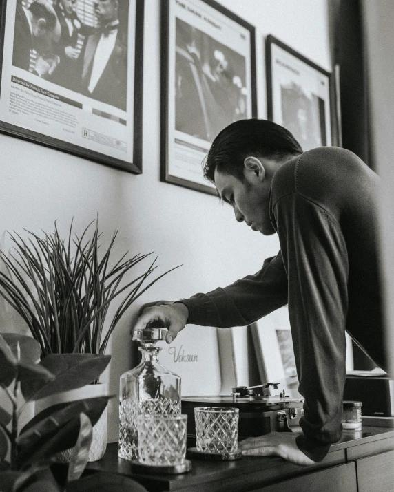 a black and white image of man reaching over to some drinks