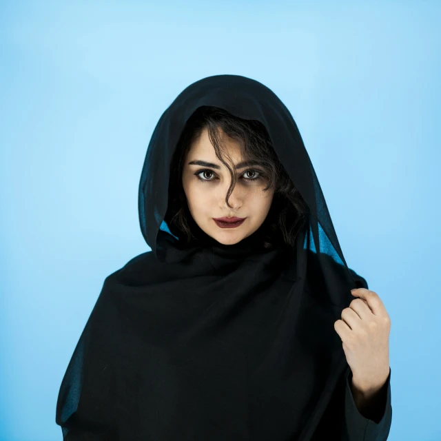 a woman in black sitting down with a blue background