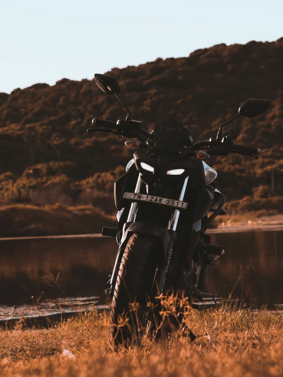 a black motorcycle parked on top of a grass field